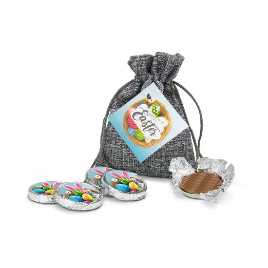 Das graue Säckchen enthält 5 Vollmilchtaler (je 8 g) im österlichen Design und trägt einen hübschen Geschenkanhänger