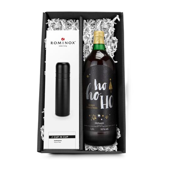 Eine ROMINOX® Isolierkanne Cup in Cup in Schwarz und eine Flasche Glühwein - verpackt in einem schwarzen Geschenkkarton.