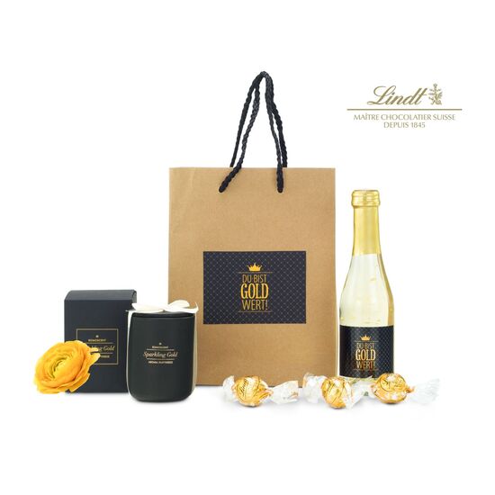 Die Tüte ist gefüllt mit "Du bist Gold wert" Secco (0,2 L), 3 goldenen Lindt Lindor Kugeln und einer ROMOSCENT® Sparkling Gold Duftkerze.