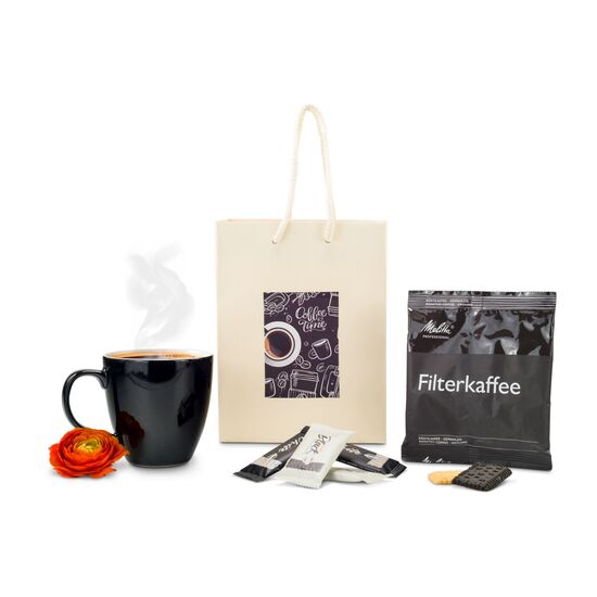 Sie erhalten eine schwarz-weiße Tasse, 1 Päckchen Melitta Röstkaffee und 4 Gebäckstücke verpackt in einer cremefarbenen Tüte mit „Coffee Time“-Sticker.